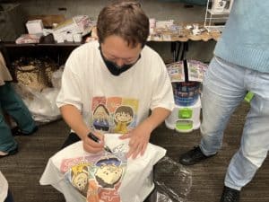 Tシャツにサインをする村上淳プロ